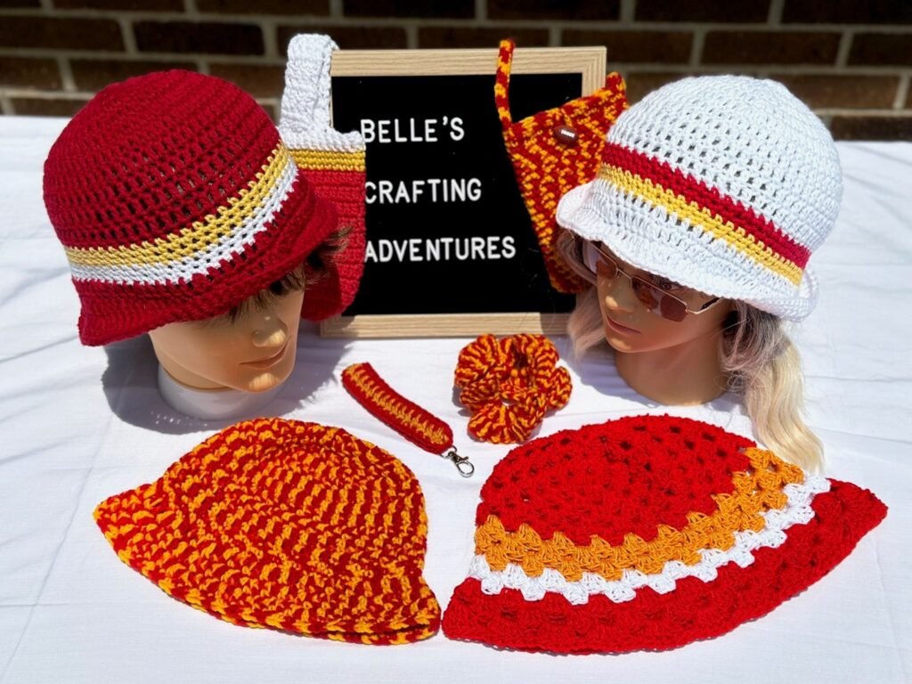 A group photo including all crocheted items themed for the Kansas City Chiefs including hats, a phone pouch, a water bottle holder, a scrunchie and a key fob.